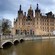 A magnificent castle with steeples and a dome near a bridge and river